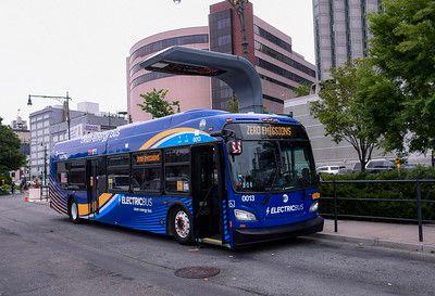An electric bus in New York City under an overhead pantograph charger.
