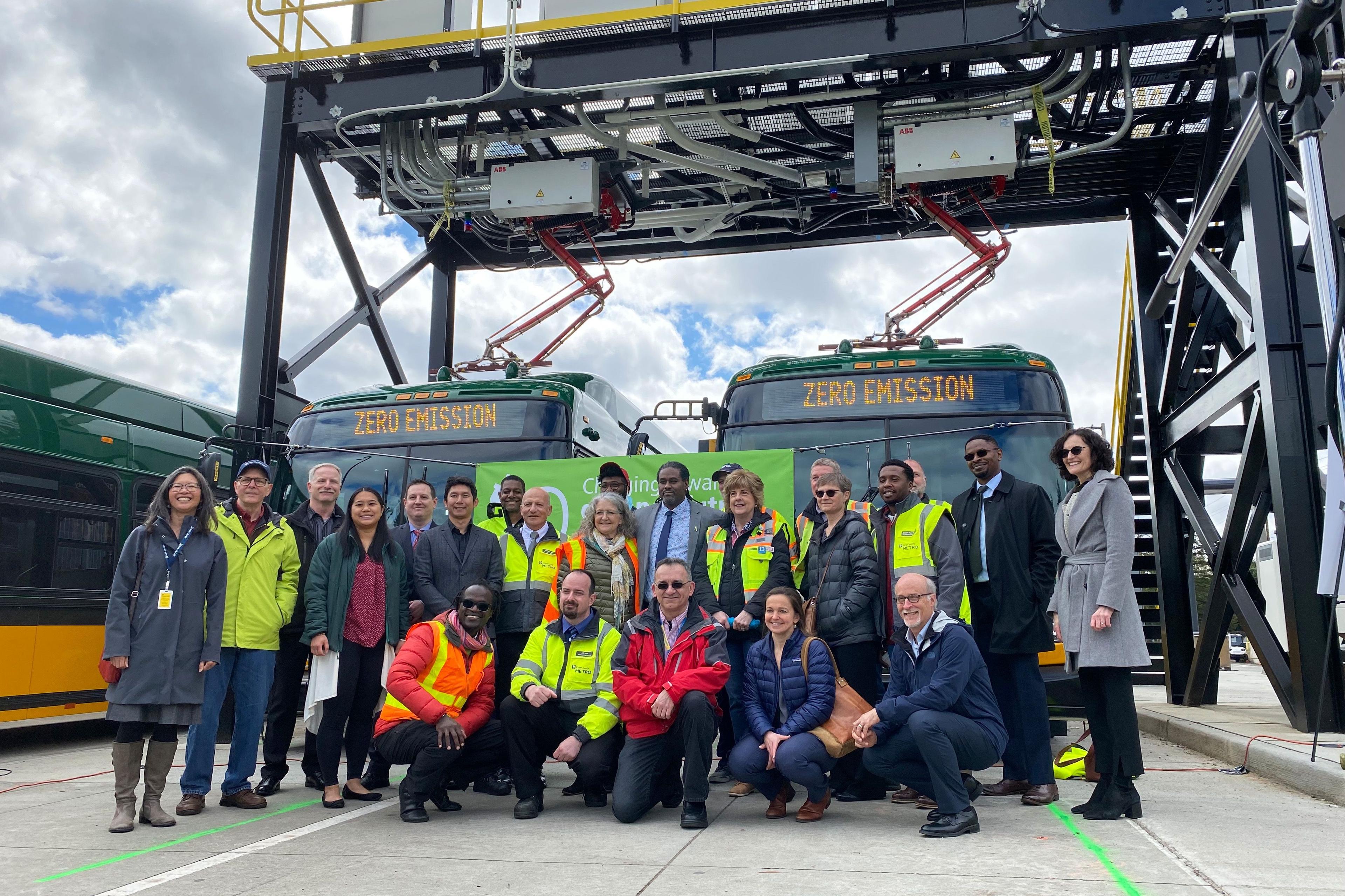 Project team in front of 2 charging e-buses