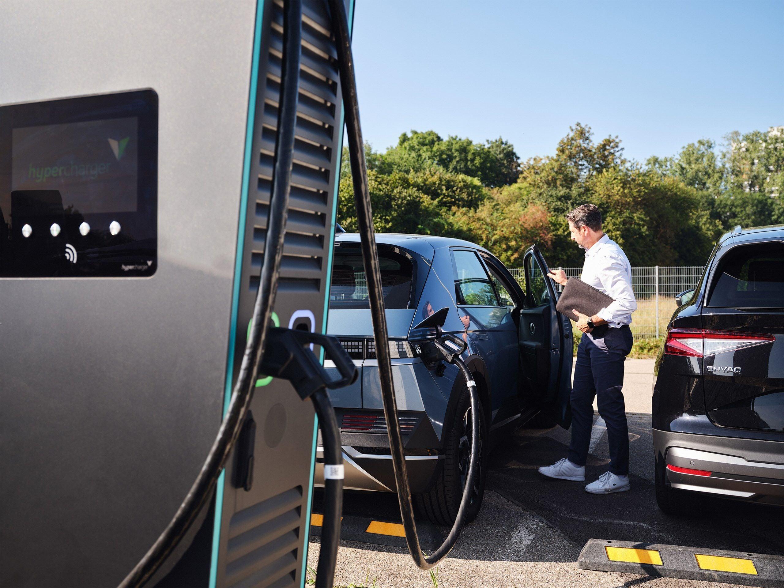 Mann lädt sein Auto an einer DC-Ladestation