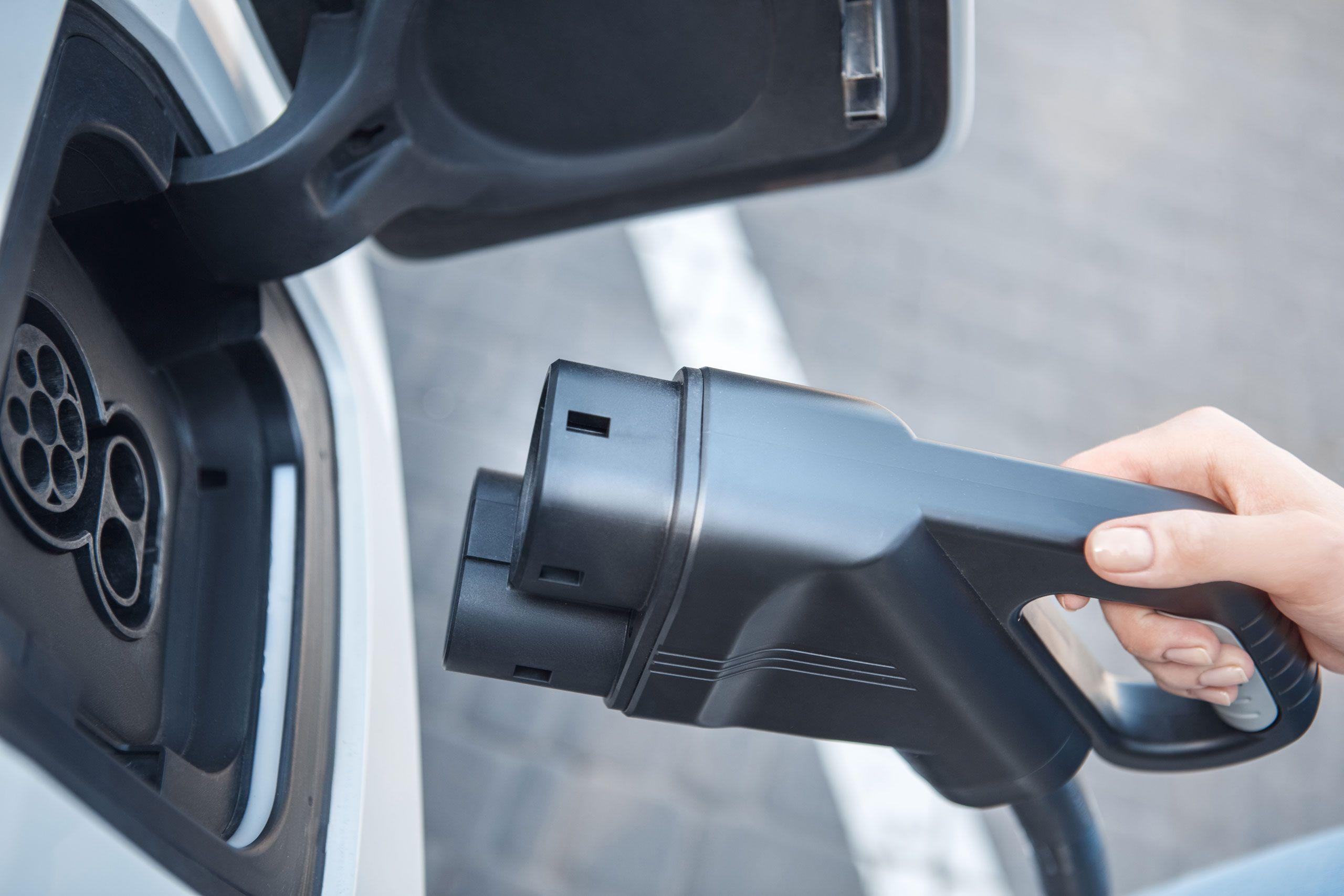 Frau steckt Ladekabel an ihr Auto an