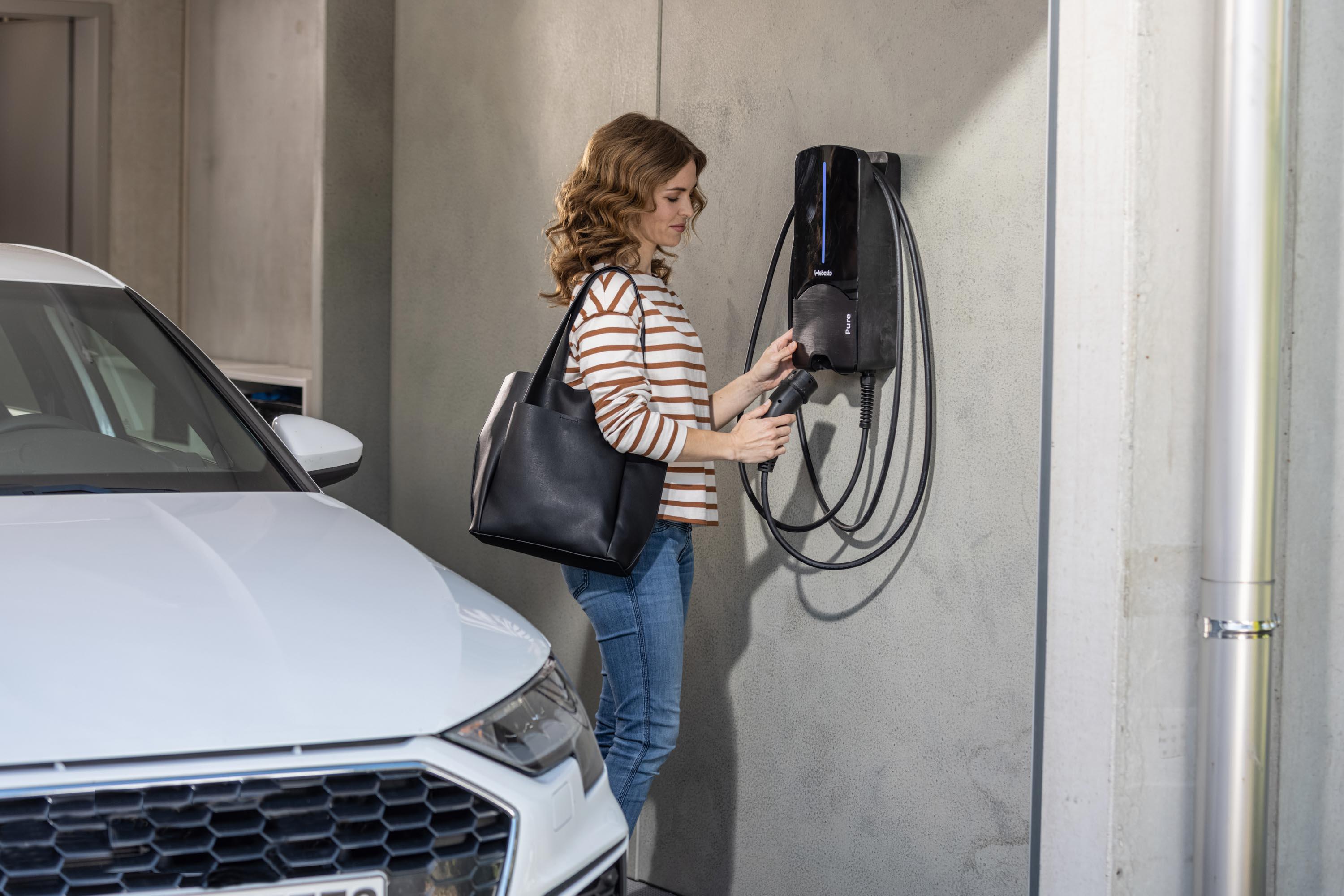 Frau steckt ihr E-Auto an eine Webasto Wallbox in der Tiefgarage an