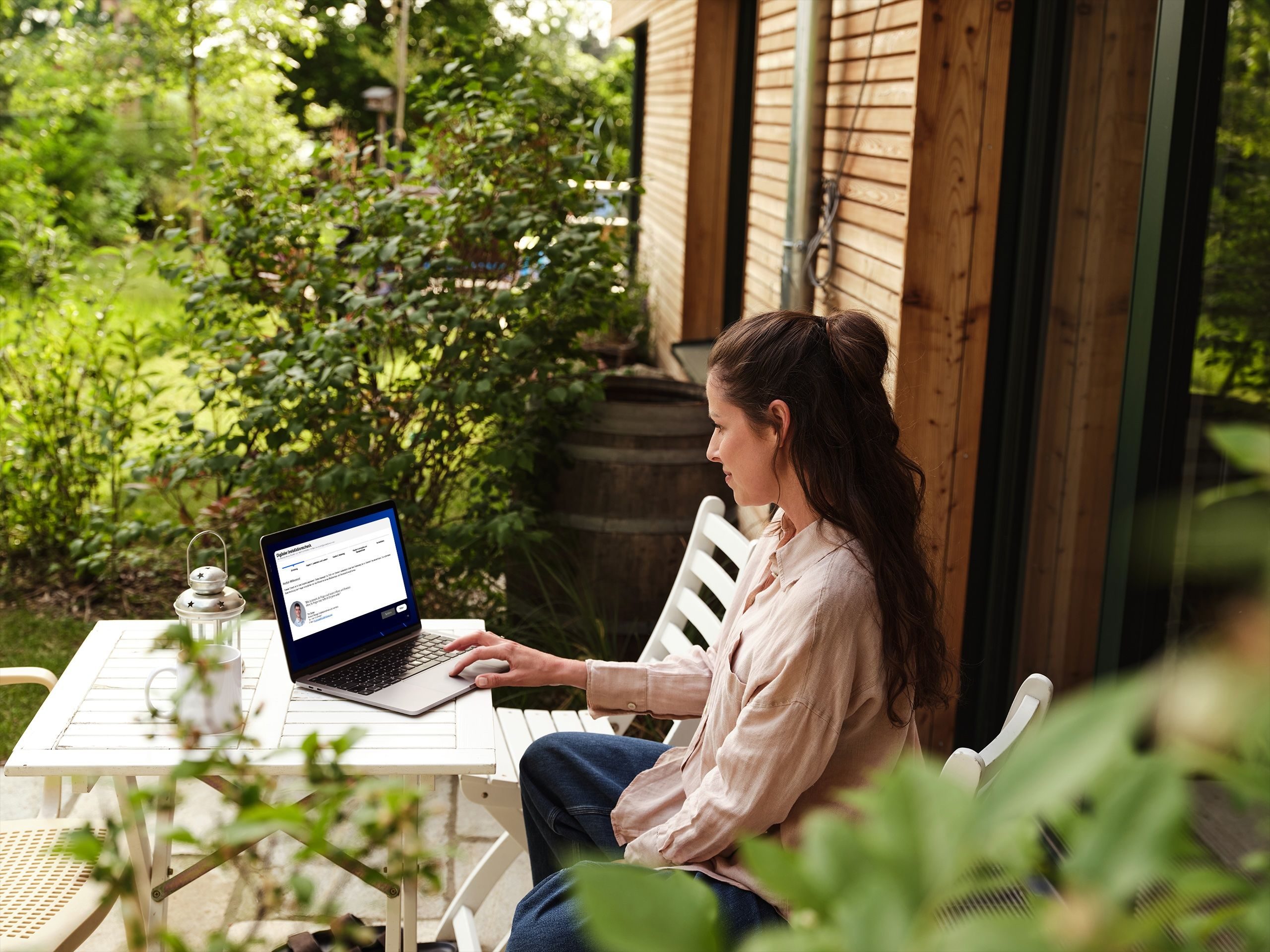 Frau sitz auf der Terrasse vor ihrem Laptop