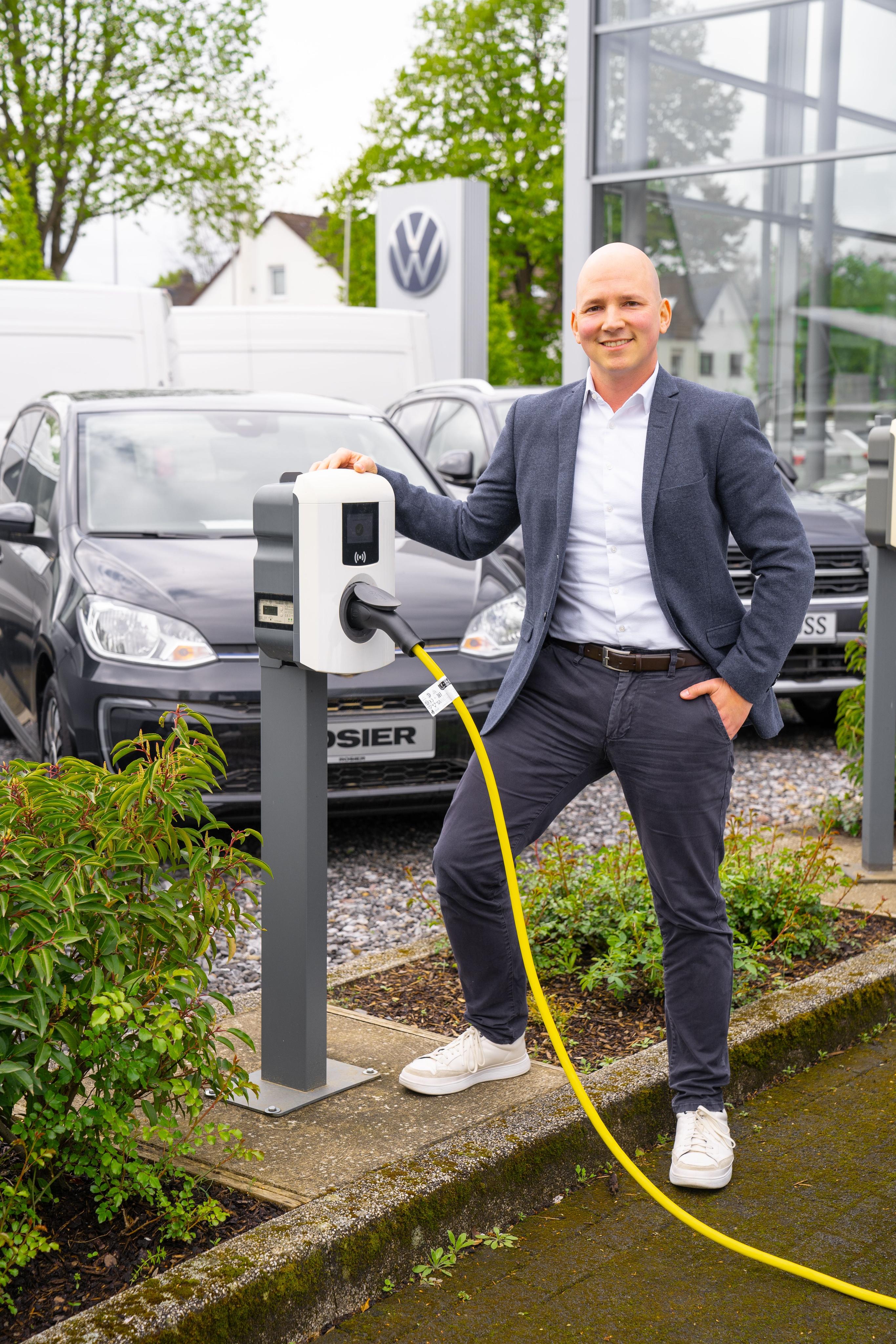 Herr Kötter Fuhrparkmanager Autohaus Rosier vor Ladestation am Firmenparkplatz