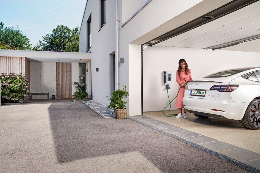 Frau lädt E-Auto in der Garage über die KEBA Wallbox