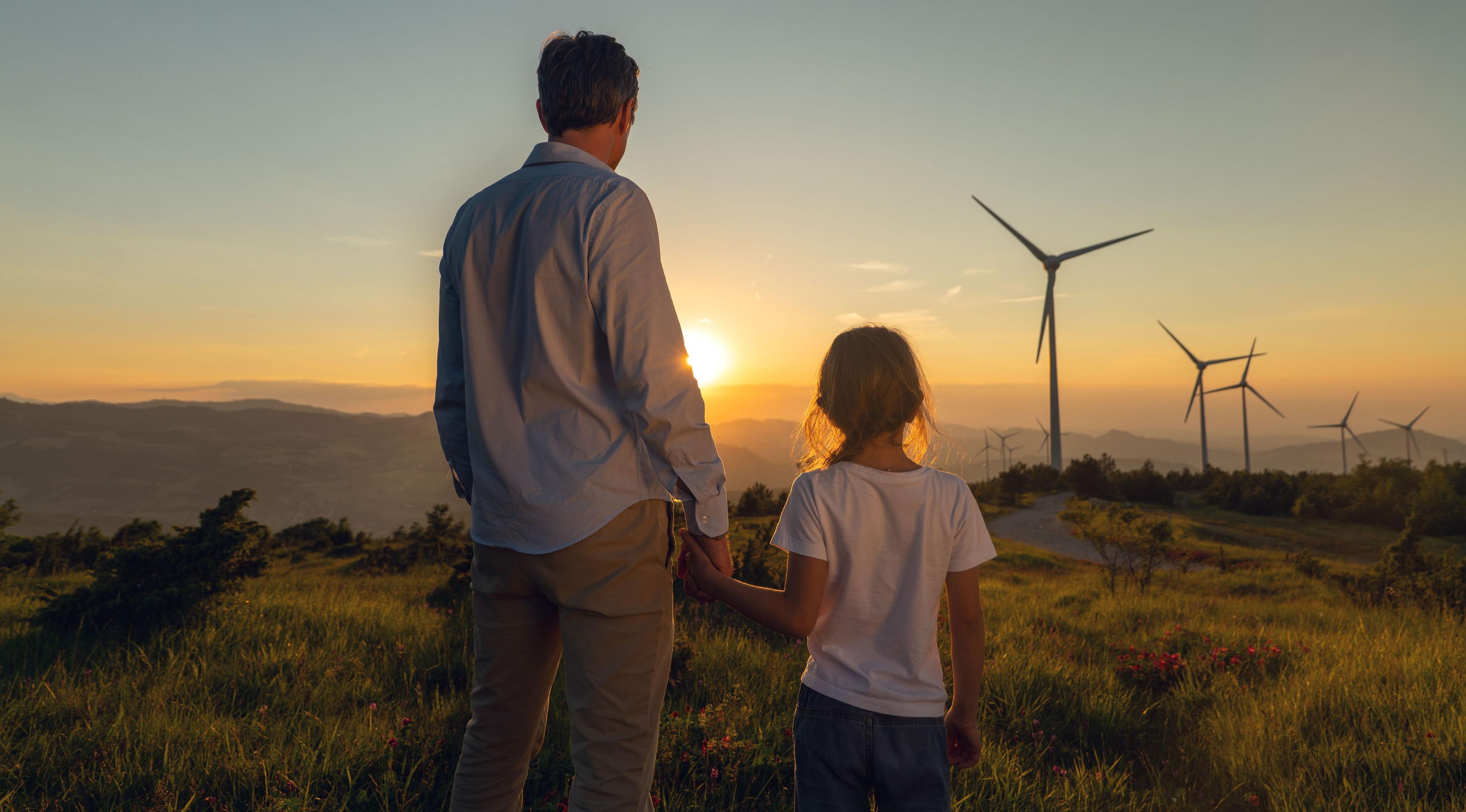Mann und Kind bei Sonnenuntergang mit Windrädern im Hintergrund