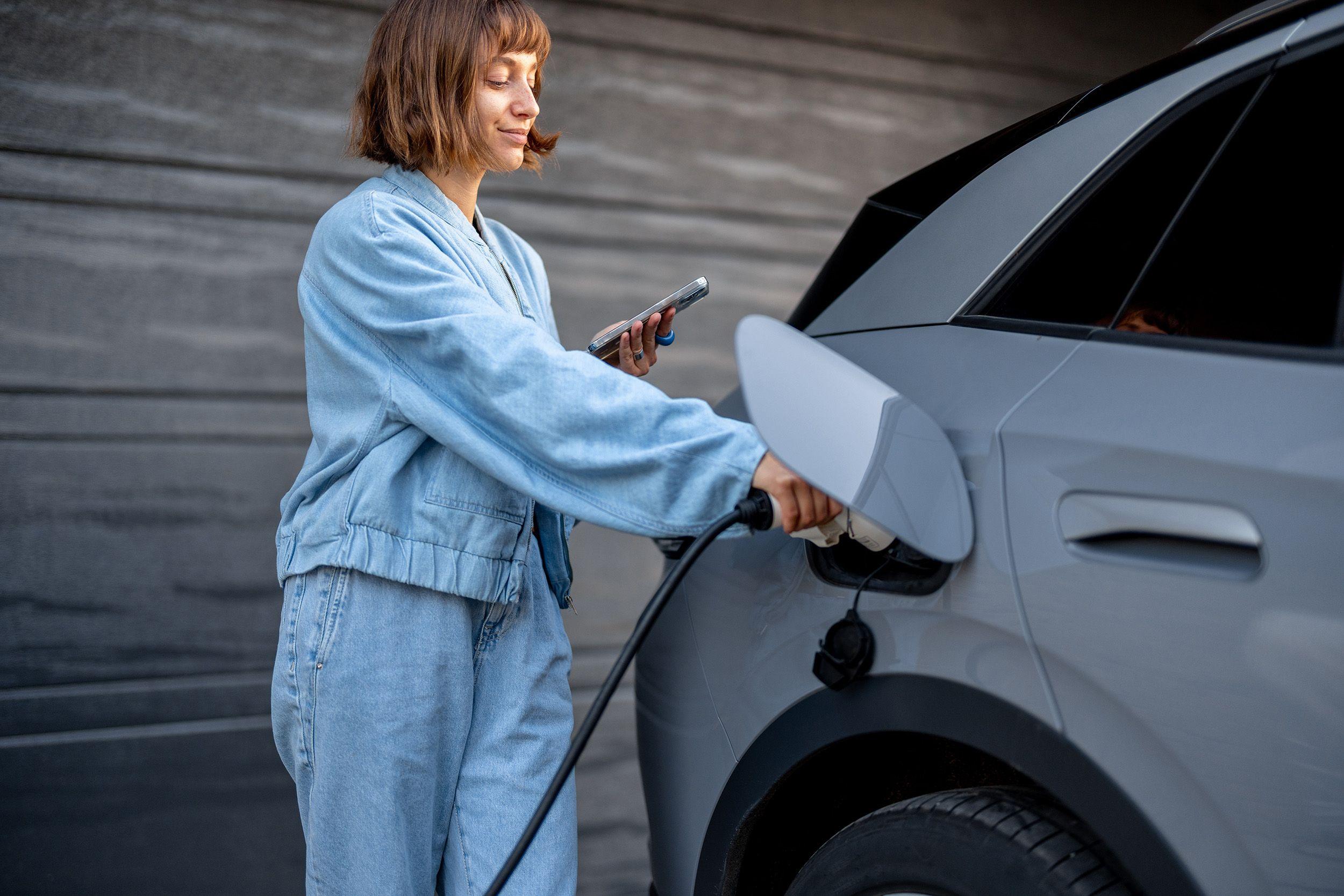 junge Frau lädt E-auto zuhause