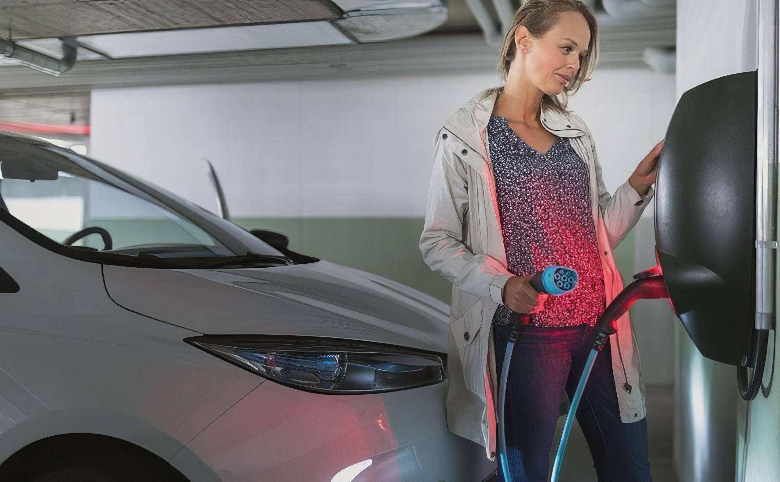 Frau lädt ihr Elektroauto am Stellplatz auf