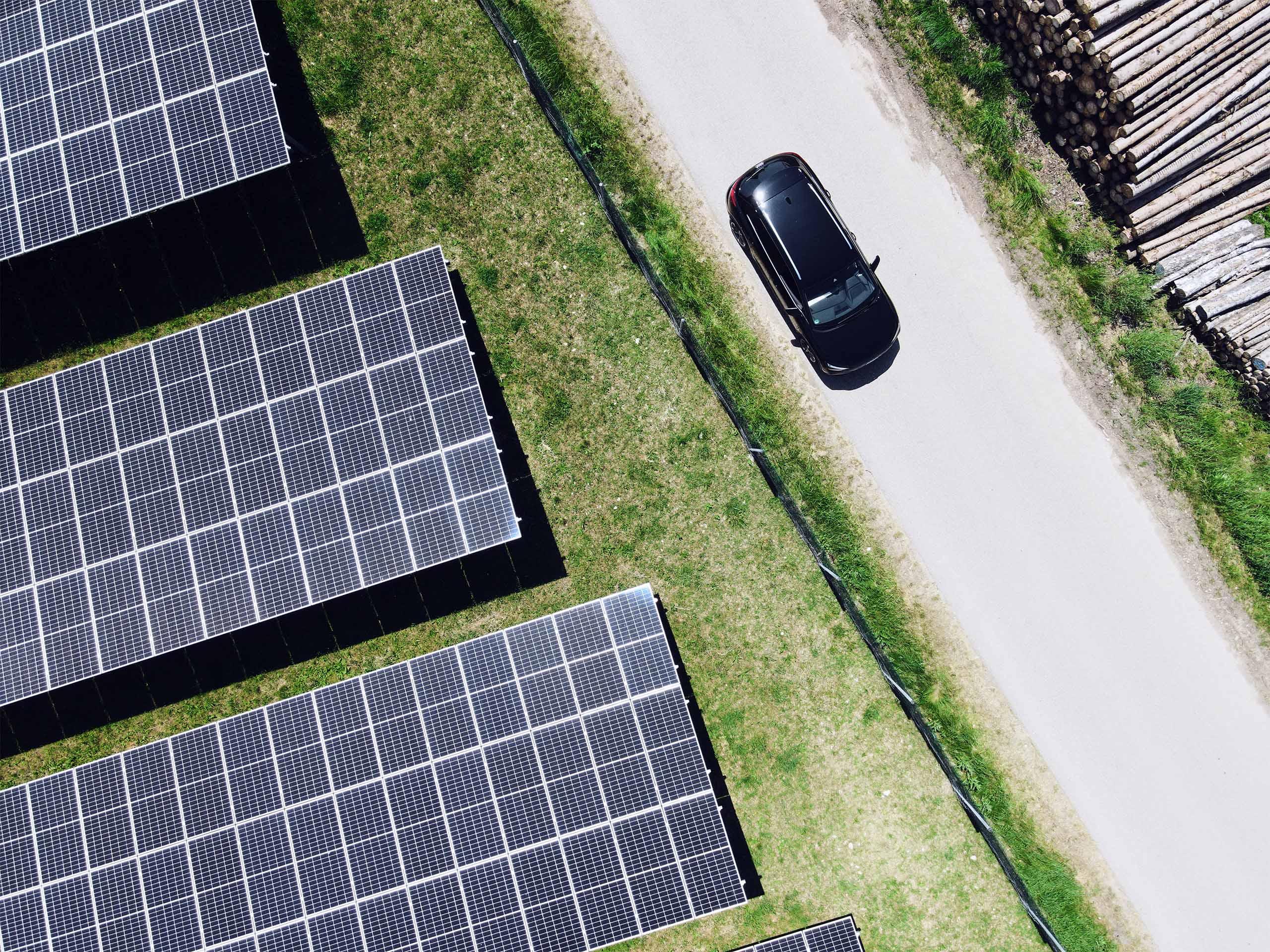 Fahrendes Elektroauto neben Solarpanelen