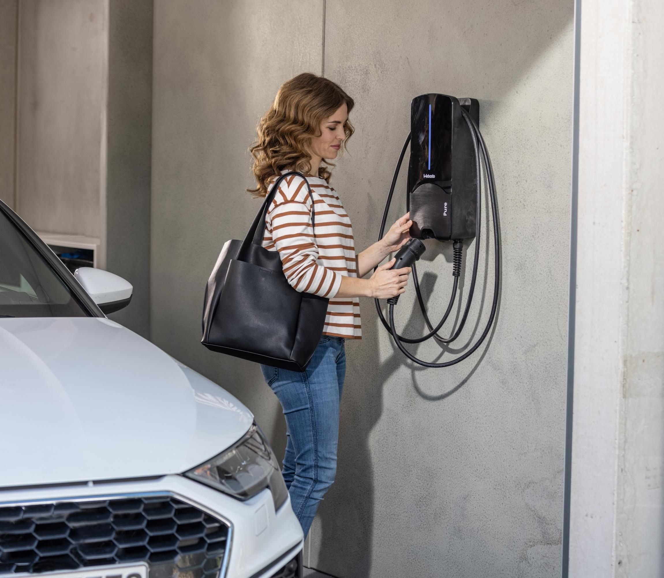 Frau steckt ihr E-Auto an eine Webasto Wallbox in der Tiefgarage an