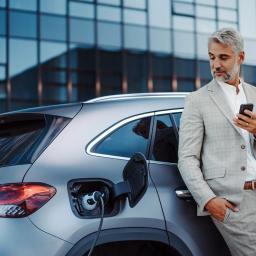 Mann lädt sein E-Auto vor Firmengebäude