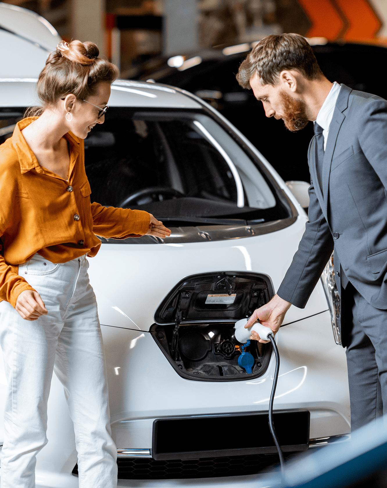 Autoverkäufer und Kundin stehen vor einem E-Auto