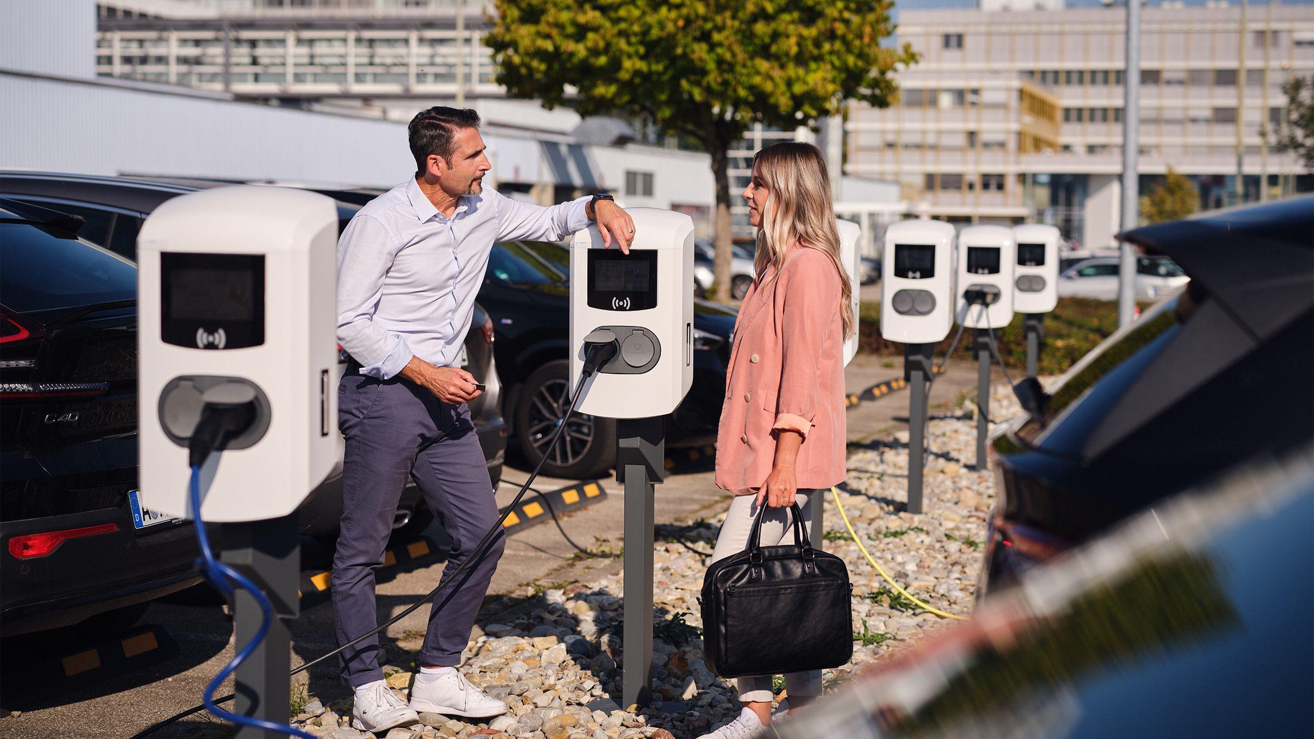 Kollegen unterhalten sich an Ladestation auf Firmenparkplatz