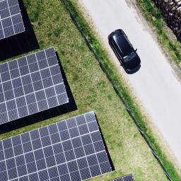 Fahrendes Elektroauto neben Solarpanelen