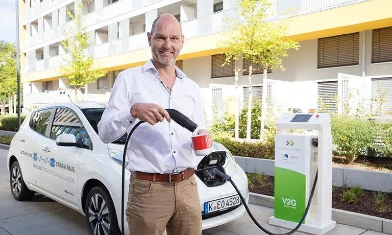 Thomas Raffeiner holds a coffee and a charging plug from a charging station in his hand