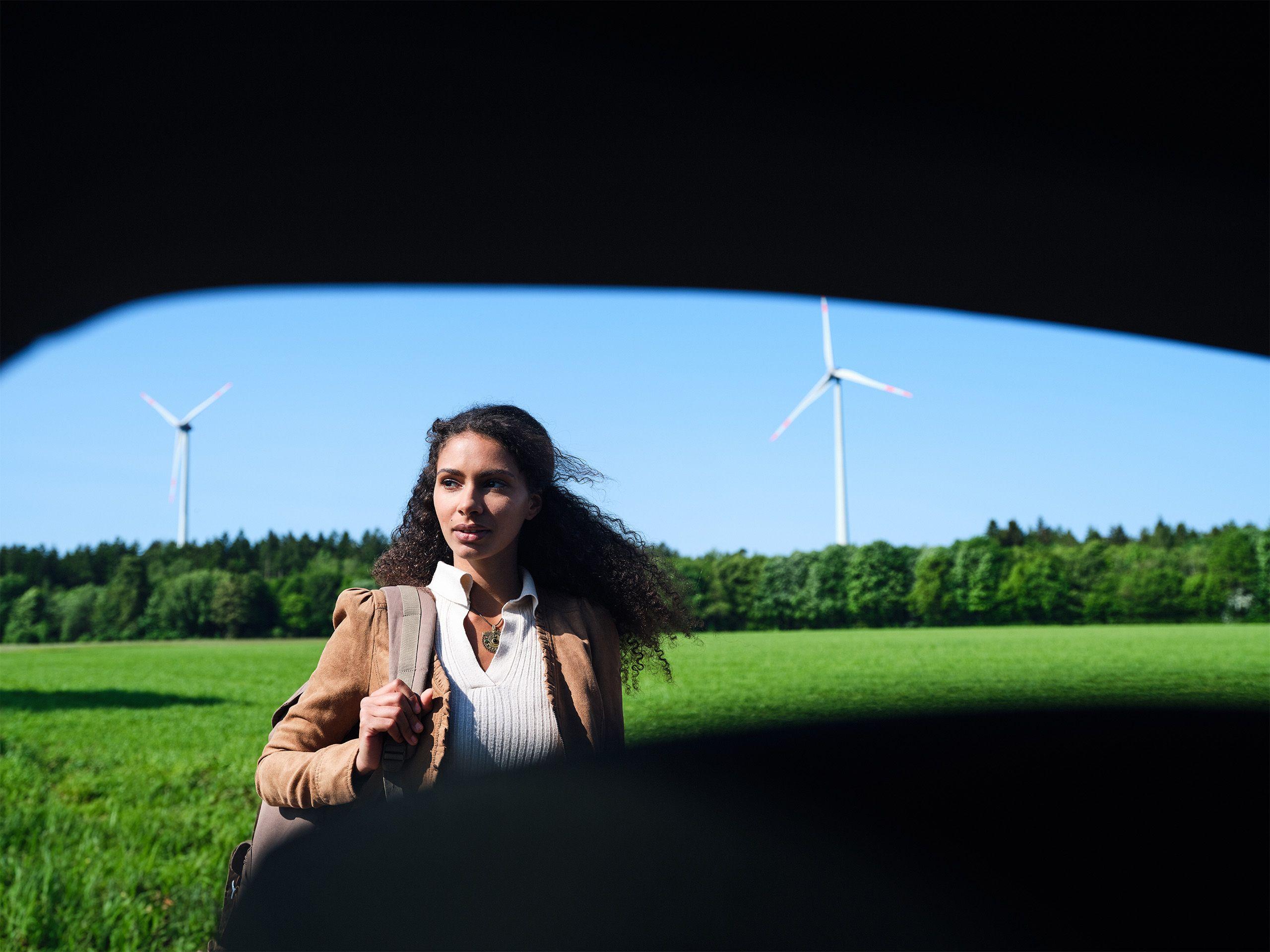 Frau steht vor Landschaft mit Windrädern