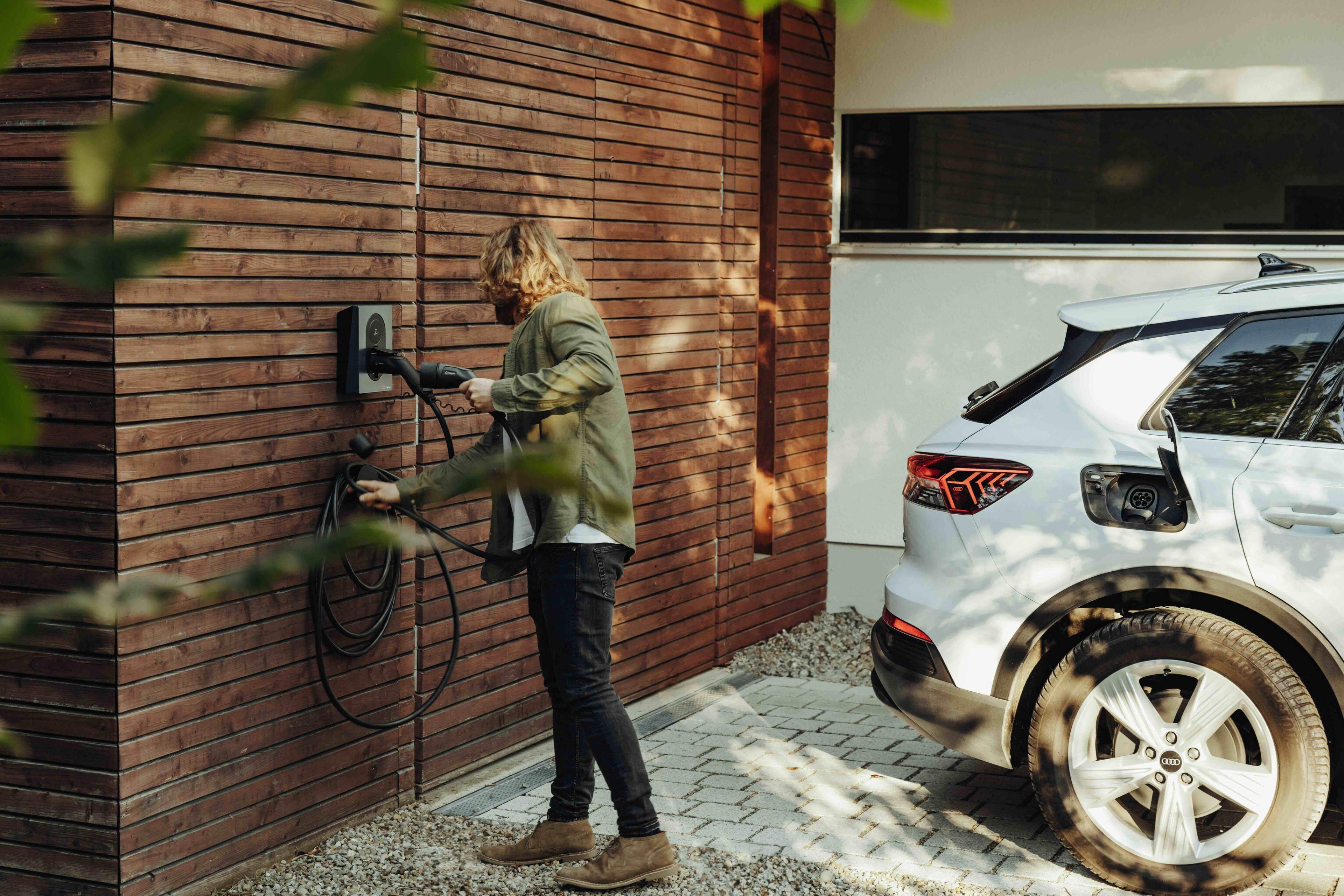 Mann lädt zu Hause sein E-Auto an der Wallbox