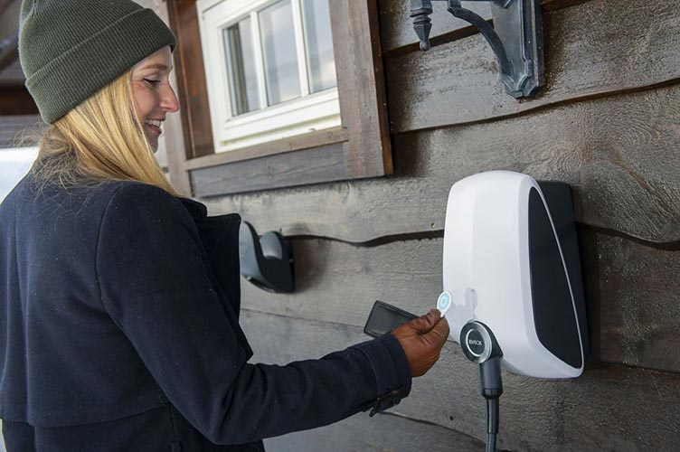 Frau mit RFID Karte an EVBox Ladestation für E-Auto