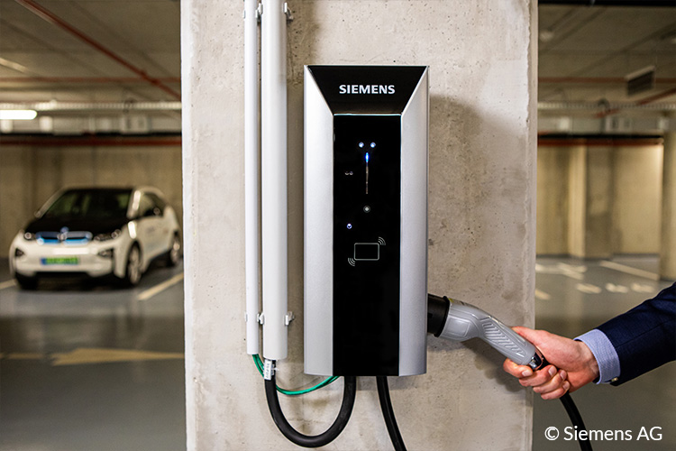Frau mit Ladestecker an EVBox Ladestation