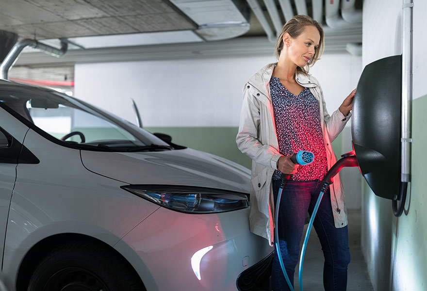 Elektroauto laden in der Tiefgarage Frau lädt an Wallbox für Elektroautos im Mietshaus