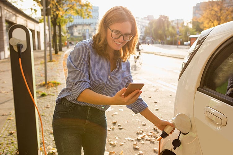 Frau lädt Auto an öffentlicher Ladestation 