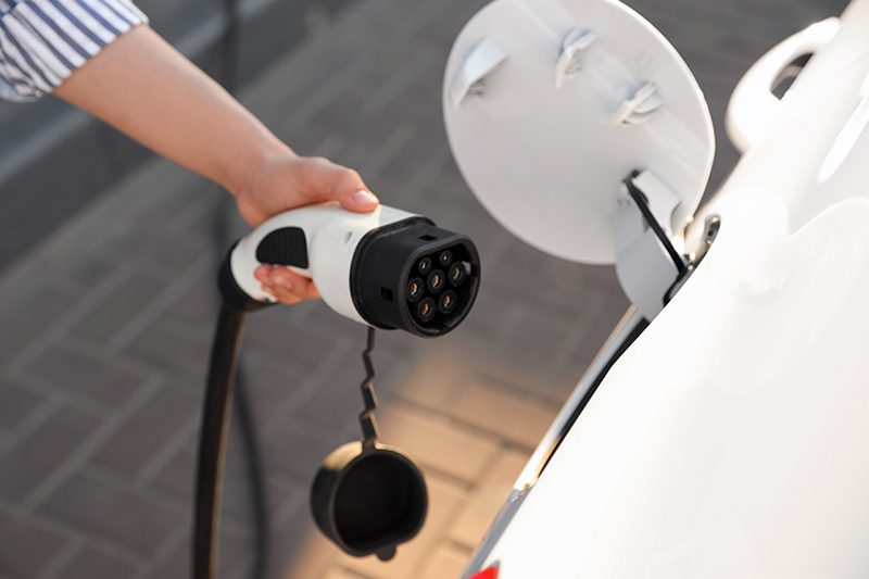Mann lädt E-Auto mit Ladekabel