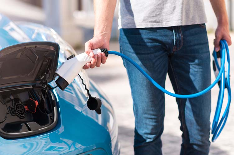 Mann lädt E-Auto mit Ladekabel