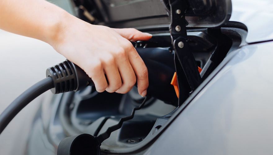 E-Auto Batterie schonend laden Frau beim Laden eines E-Autos
